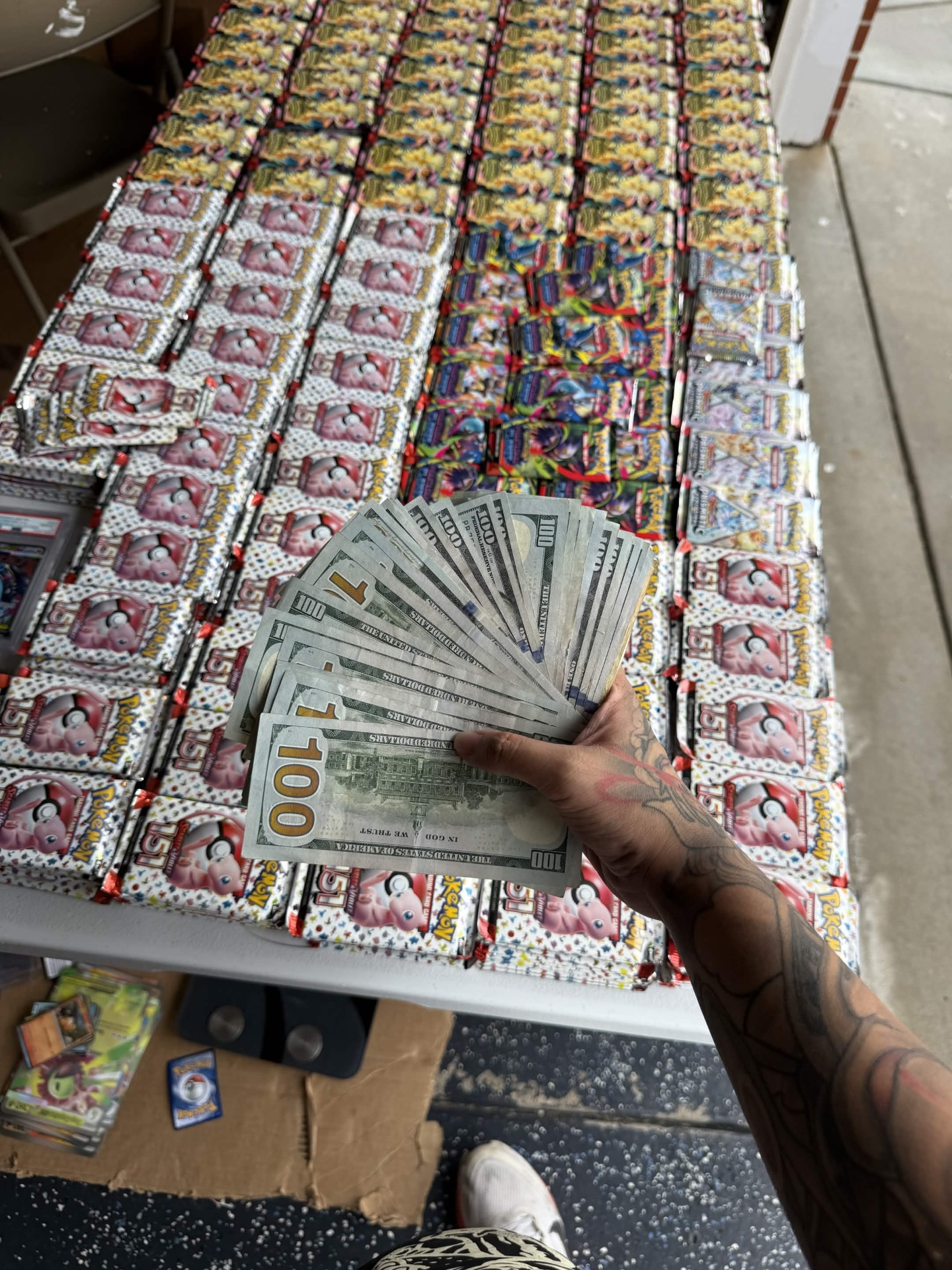 Table of Pokemon 151 packs with cash fan